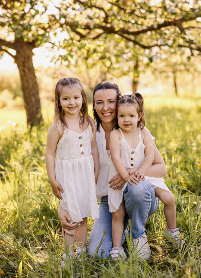 ungezwungene-Familienfotos-Wuerzburg Mama und Töchter stehen in Wiese und lachen